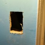 Inlet hole cut in drywall for central vacuum installation in an existing home.