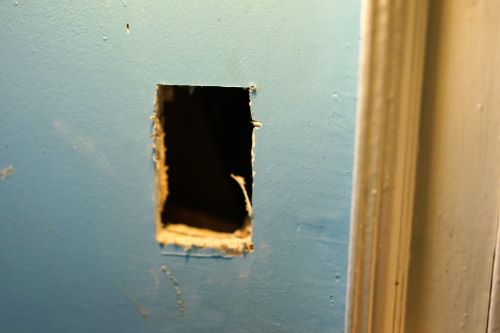 Inlet hole cut in drywall for central vacuum installation in an existing home.