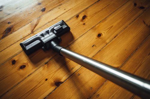Vacuuming with hardwood floor vacuum attachment on wood floor.